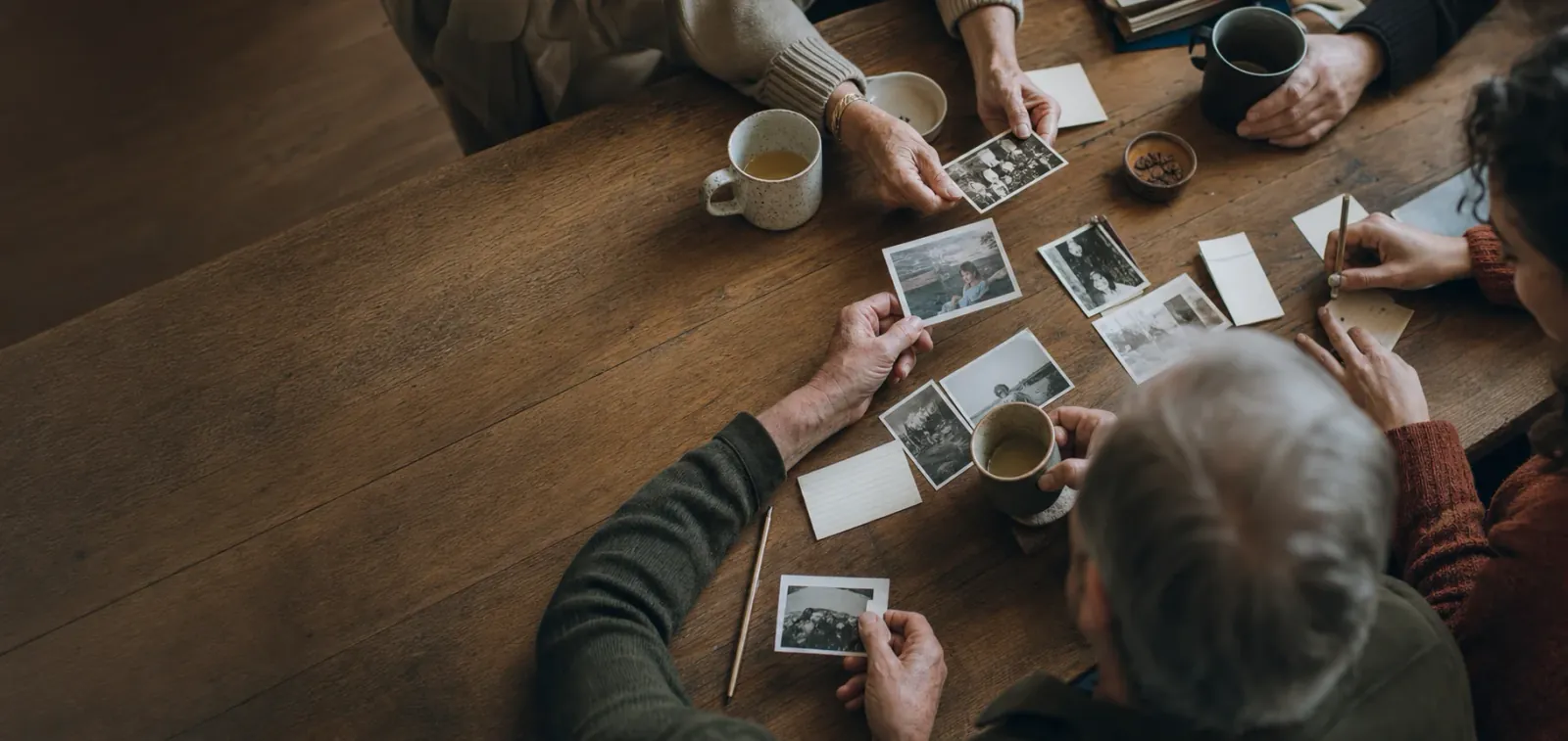 Family photographs and handwritten notes spread across a kitchen table
